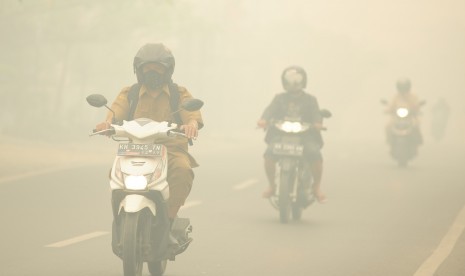 Sejumlah pengendara motor melintasi jalan yang diselimuti kabut asap pekat di Palangkaraya, Kalimantan Tengah, Selasa (27/10). 