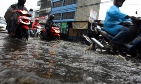 Sejumlah pengendara motor mencoba menerobos genangan air di Jalan Dewi Sartika, Ciputat, Tangerang Selatan, Banten, Sabtu (7/11).