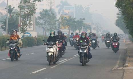 Sejumlah pengendara motor mengenakan masker saat melintasi jembatan yang diselimuti kabut asap di Pontianak, Kalbar, Jumat (24/8).