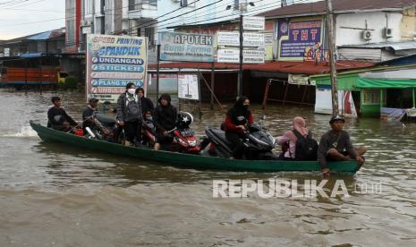 Sejumlah pengendara motor menggunakan jasa ojek penyeberangan saat melintasi banjir yang merendam jalan Lintas Melawi di Kabupaten Sintang, Kalimantan Barat, Selasa (16/11/2021). Hingga kini kawasan Lintas Melawi yang merupakan pusat perdagangan Kota Sintang dan jalur utama menuju Kabupaten Kapuas Hulu tersebut masih terendam banjir.