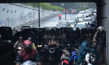 Sejumlah pengendara sepeda motor berteduh menunggu hujan reda di underpass Pasar Minggu-Kalibata, Jakarta Selatan, Senin (12/1). (Republika/Raisan Al Farisi)