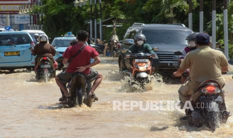 Sejumlah pengendara sepeda motor dan mobil melintasi jalur wisata Mataram - Senggigi yang terendam banjir di Desa Meninting, Kecamatan Batulayar, Lombok Barat, NTB, Selasa (7/12). Jalan utama dari Kota Mataram menuju kawasan wisata Senggigi terendam banjir mencapai 1 meter akibat hujan deras dan luapan air sungai Meninting pada Senin (6/12). 