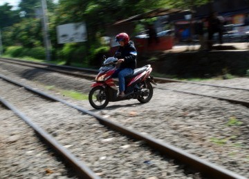 Sejumlah pengendara sepeda motor melintasi perlintasan rel kereta api tanpa palang pintu di Palmerah, Jakarta, Rabu (21/3). (Republika/Agung Fatma Putra)