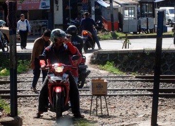 Sejumlah pengendara sepeda motor melintasi perlintasan rel kereta api tanpa palang pintu di Palmerah, Jakarta, Rabu (21/3). (Republika/Agung Fatma Putra)