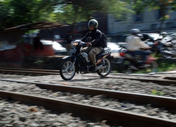 Sejumlah pengendara sepeda motor melintasi perlintasan rel kereta api tanpa palang pintu di Palmerah, Jakarta, Rabu (21/3). (Republika/Agung Fatma Putra)