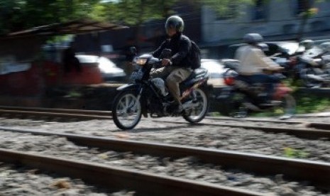 Sejumlah pengendara sepeda motor melintasi perlintasan rel kereta api tanpa palang pintu di Palmerah, Jakarta, Rabu (21/3). (Republika/Agung Fatma Putra)