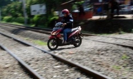 Sejumlah pengendara sepeda motor melintasi perlintasan rel kereta api tanpa palang pintu di Palmerah, Jakarta, Rabu (21/3). (Republika/Agung Fatma Putra)