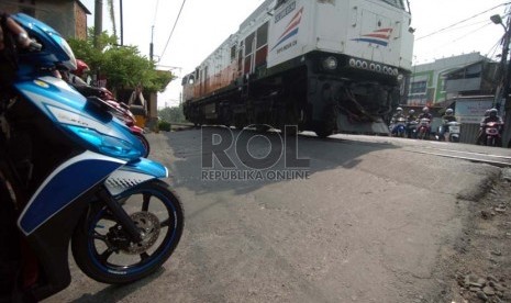 Sejumlah pengendara sepeda motor menunggu di depan pintu perlintasan kereta api kawasan Kalibata, Jakarta Selatan, Jumat (19/9).( Republika/Raisan Al Farisi)