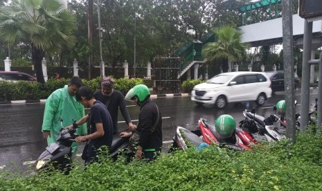 Sejumlah pengojek daring berusaha menyalakan sepeda motor yang terendam banjir di Jalan Asia Afrika, Senayan, Jakarta Pusat, Selasa (17/12).