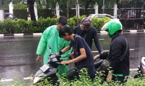 Sejumlah pengojek daring berusaha menyalakan sepeda motor yang terendam banjir di Jalan Asia Afrika, Senayan, Jakarta Pusat, Selasa (17/12).