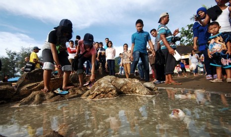 Sejumlah pengunjung berada di dekat batu Malin Kundang yang terendam air laut, di Pantai Air Manis, Padang, Sumatera Barat, Sabtu (3/1)