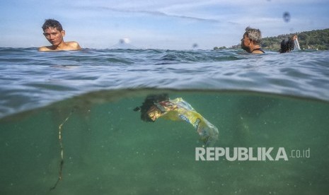 Sejumlah pengunjung berenang di dekat sampah plastik yang hanyut terbawa arus di pantai wisata Senggigi, Lombok Barat, NTB. 