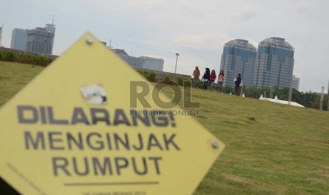 Sejumlah pengunjung berjalan di rumput dengan mengabaikan papan aturan yang terpasang di Monumen Nasional (Monas) Jakarta Pusat, Kamis, (4/12).