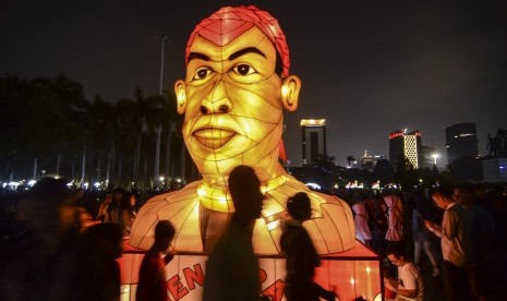 Sejumlah pengunjung melintas di dekat lampion karakter pahlawan nasional Jenderal Besar Sudirman pada acara Festival of Light di Monas, Jakarta Pusat, Sabtu (17/8). Festival lampion dan laser bertemakan HUT ke-74 Kemerdekaan RI itu berlangsung dari 14-25 Agustus 2019.