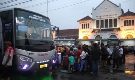 Sejumlah penumpang kereta menunggu jemputan bus untuk diantar ke tujuan mereka di Stasiun Cirebon, Jawa Barat, Jumat (23/2). Akibat banjir luapan sungai Cisanggarung yang merendam perlintasan kereta api membuat jadwal keberangkatan kereta terganggu. 