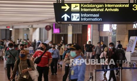 Sejumlah penumpang pesawat berjalan di area Terminal 2F Internasional Bandara Soekarno Hatta, Tangerang, Banten, Jumat (17/12). Menteri Kesehatan Budi Gunadi Sadikin meminta masyarakat agar tak melakukan perjalanan ke luar negeri jika tidak sangat mendesak.