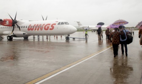 Sejumlah penumpang pesawat menggunakan payung berjalan menuju pesawat di Bandara El Tari Kupang, NTT Kamis, (28/12/18).