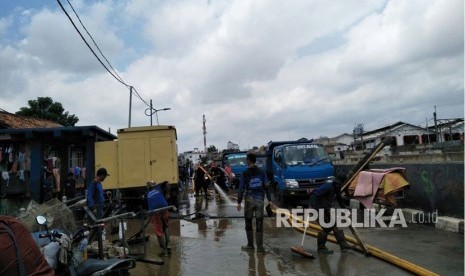 Sejumlah personel dari Suku Dinas Sumber Daya Air Jakarta Timur membersihkan sisa lumpur akibat luapan Sungai Ciliwung, kawasan Kampung Melayu, Jumat (9/2).