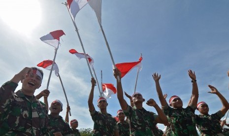 Sejumlah personel TNI melambaikan bendera merah putih.