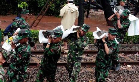 Sejumlah personel TNI membawa batu dan pasir pada perbaikan tanggul Banjir Kanal Barat (BKB) yang jebol di Jalan Latuharhary, Jakarta, Jumat (18/1). Jebolnya tanggul itu mengakibatkan sebagian Jalan Thamrin dan Sudirman terendam air.