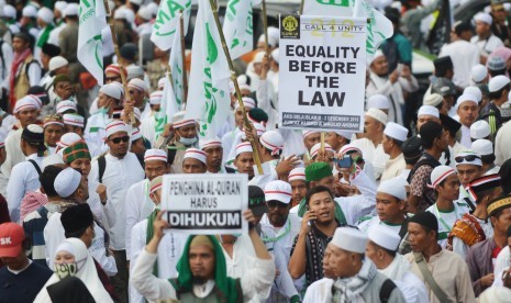 Sejumlah peserta aksi membawa poster saat long march menuju Monas untuk mengikuti aksi 212 atau 2 Desember di Jalan MH Thamrin, Jakarta, Jumat (2/12). 