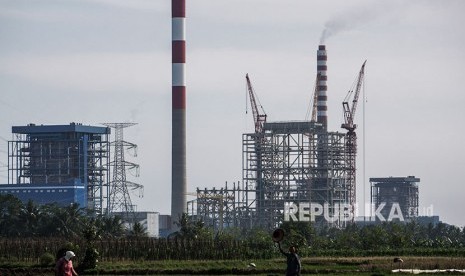 Sejumlah petani menggarap lahan sawahnya dengan latar belakang proyek pembangkit listrik tenaga uap (PLTU) Cilacap Ekspansi Fase 2, 1x1.000 Megawatt di Desa Karangkandri, Kesugihan, Cilacap, Jawa Tengah, Selasa (24/4).