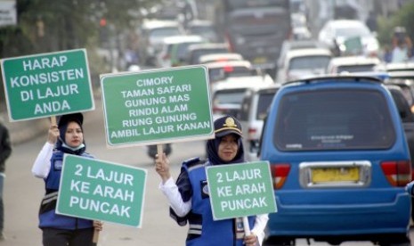 Sejumlah petugas Badan Pengelola Transportasi Jabodetabek (BPTJ) membentangkan papan informasi sosialisasi sistem kanalisasi di Jalur Puncak, Bogor, Jawa Barat, Ahad (27/10/2019). Sosialisasai tersebut untuk menginformasikan penerapan rekayasa lalu lintas kanalisasi 2:1, sebagai pengganti sistem satu arah (one way). 