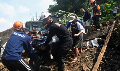 Sejumlah petugas BPBD Kota Bogor bersama warga mengevakuasi sepeda motor yang tertimpa longsor di area pemancingan umum, Gang Kepatihan, Kelurahan Kalapa, Kota Bogor, Jawa Barat, Rabu (12/10/2022). BPBD Kota Bogor mencatat satu warga tewas dan satu warga lainnya mengalami luka-luka akibat tertimpa longsoran tebing setinggi 15 meter di area pemancingan umum tersebut saat wilayah Kota Bogor diguyur hujan deras disertai angin kencang pada Selasa (11/10/2022) sore. 