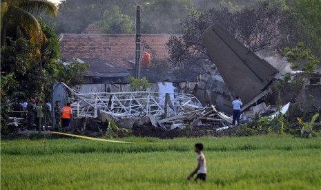 Sejumlah petugas dan warga menyaksikan bangkai pesawat Fokker 27 yang jatuh di komplek perumahan Rajawali kawasan Lapangan Udara Halim Perdana Kusuma, Jakarta, Kamis (21/6). 