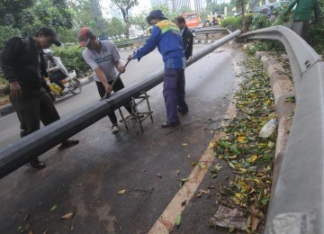 Sejumlah petugas dibantu warga mengevakuasi tiang lampu penerangan jalan yang tumbang akibat angin ribut di kawasan Mampang Prapatan, Jakarta Selatan, Rabu (26/10). (Republika/Aditya Pradana Putra)