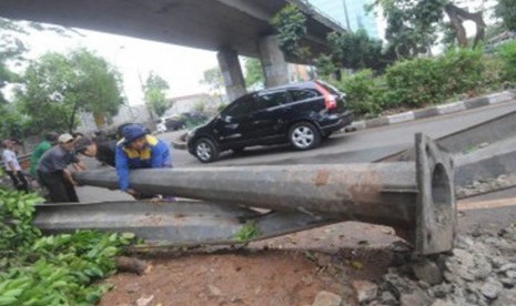 Sejumlah petugas dibantu warga mengevakuasi tiang lampu penerangan jalan yang tumbang akibat angin ribut di kawasan Mampang Prapatan, Jakarta Selatan, Rabu (26/10). (Republika/Aditya Pradana Putra)