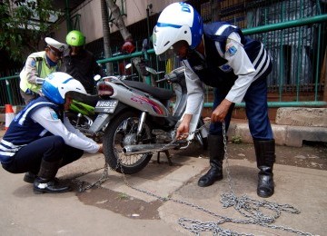 Sejumlah petugas Dinas Perhubungan Jakarta Barat mengembok ratusan sepada motor yang parkir liar saat menggelar razia parkir di depan Harco Glodok , Jakarta Barat, Selasa (28/2). (Republika/Prayogi)