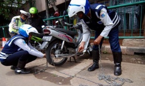 Sejumlah petugas Dinas Perhubungan Jakarta Barat mengembok ratusan sepada motor yang parkir liar saat menggelar razia parkir di depan Harco Glodok , Jakarta Barat, Selasa (28/2). (Republika/Prayogi)