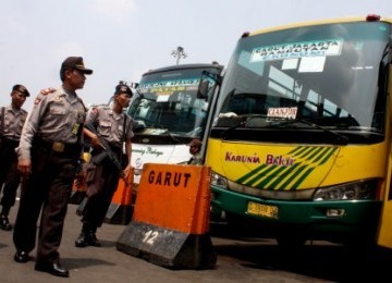 Sejumlah petugas kepolisian dan Pasukan Brimob Polda Metro Jaya melintas depan bus antar kota antar provinsi saat pengamanan terminal di terminal Kampung Rambutan, Jakarta Timur, Selasa (23/8). 