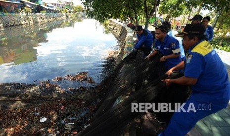 Sejumlah petugas melepaskan kain waring atau jaring yang menutupi Kali Item di kawasan Kemayoran, Jakarta Utara, Kamis (15/11). 