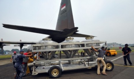 Sejumlah petugas membawa tangki berisi garam untuk dinaikkan ke pesawat Hercules C-130 di Lanud Halim Perdana Kusuma Jakarta, Sabtu (15/3). BPPT bersama TNI AU melakukan modifikasi cuaca dengan menyebar sekitar lima ton garam di Kawasan Riau guna memadamka