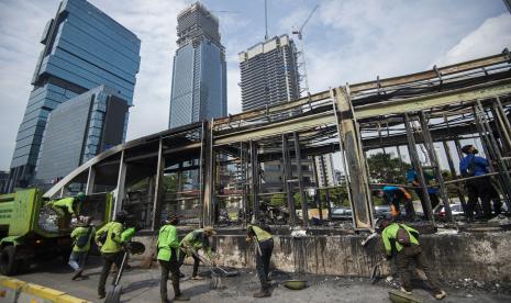 Sejumlah petugas membersihkan puing Halte Bus Trans-Jakarta Tosari yang hangus saat kericuhan unjuk rasa menolak pengesahan Undang-Undang Cipta Kerja di Jalan MH. Thamrin, Jakarta, Jumat (9/10/2020). Sejumlah fasilitas umum rusak dalam kericuhan yang terjadi Kamis (8/10). 