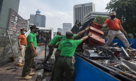 Sejumlah petugas membersihkan puing Halte Bus Trans-Jakarta Tosari yang hangus saat kericuhan unjuk rasa menolak pengesahan Undang-Undang Cipta Kerja di Jalan MH. Thamrin, Jakarta, Jumat (9/10/2020). Sejumlah fasilitas umum rusak dalam kericuhan yang terjadi Kamis (8/10).