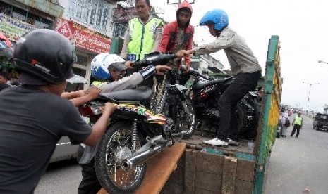 Sejumlah petugas mengangkut sepeda motor milik siswa yang tidak memiliki surat kendaraan ke dalam bak truk saat razia geng motor.