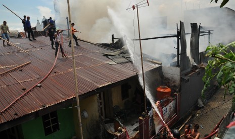 Sejumlah petugas pemadam kebakaran dibantu masyarakat berusaha memadamkan api yang melanda kawasan padat perumahan di Rappokalling Timur, Makassar, Sulsel, Rabu (28/3). Api yang di duga akibat hubungan arus pendek listrik itu menyebabkan Ttga rumah habis t