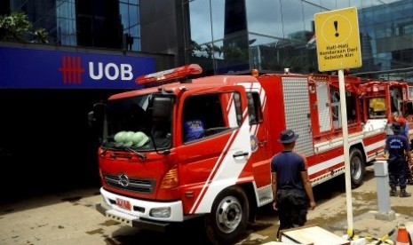 Sejumlah petugas pemadam kebakaran melintas diantara truk pemadam kebakaran yang digunakan untuk melakukan penyedotan air di Basement Plaza UOB, Jakarta Pusat, Ahad (20/1). 