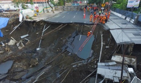 Sejumlah petugas pemadam kebakaran memeriksa kondisi tanah ambles di Jalan Raya Gubeng, Surabaya, Jawa Timur, Rabu (19/12/2018). Jalan raya tersebut ambles sedalam sekitar 20 meter dengan lebar 30 meter pada Selasa (18/12/2018) malam diduga karena proyek pembangunan gedung di sekitar lokasi. 