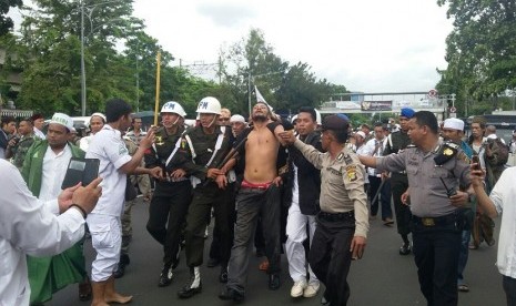 Sejumlah petugas Polisi Militer (PM) mengamankan seorang pria  diduga mabok di pintu timur Stasiun Gambir, Jakarta Pusat, usai berlangsungnya aksi damai 212 pada hari ini, Jumat (2/12). 