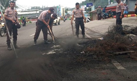 Sejumlah polisi membersihkan sisa kerusuhan di salah satu ruas jalan di Manokwari, Papua Barat, Selasa (20/8/2019).