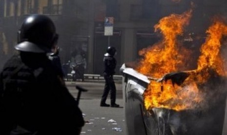 Sejumlah polisi Spanyol berdiri dekat tong sampah terbakar. Terjadi bentrok antar massa protes dengan aparat dan aksi kekerasan dalam demonstrasi yang berujung rusuh di Barcelona