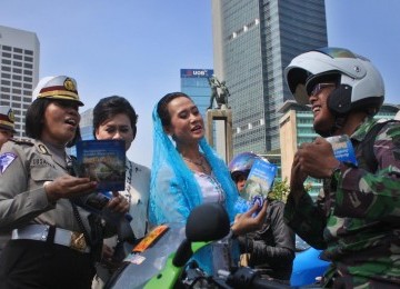 Sejumlah Polisi Wanita (Polwan) memakai Kebaya membagikan Brosur sosialisasi Undang-undang Lalu lintas kepada pengendara bermotor dalam memperingati Hari Kartini di kawasan MH. Thamrin, Jakarta, Kamis (21/4). 