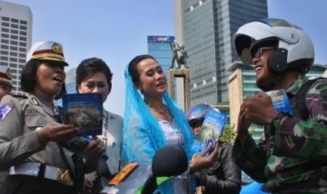 Sejumlah Polisi Wanita (Polwan) memakai Kebaya membagikan Brosur sosialisasi Undang-undang Lalu lintas kepada pengendara bermotor dalam memperingati Hari Kartini di kawasan MH. Thamrin, Jakarta, Kamis (21/4). 