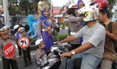 Sejumlah polisi wanita (polwan) memakaikan helm kepada pengendara motor (Ilustrasi).