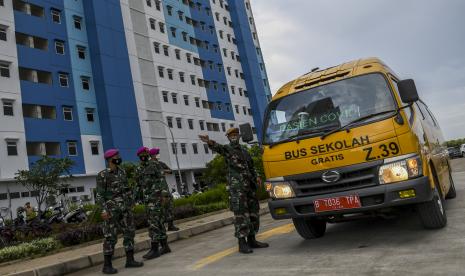 Sejumlah prajurit TNI mengarahkan bus sekolah yang membawa pasien COVID-19 dengan kategori Orang Tanpa Gejala (OTG) di Rumah Susun Nagrak, Cilincing, Jakarta Utara, Senin (21/6/2021). Data Satuan Tugas Penanganan COVID-19 per hari Senin (21/6) menyebutkan kasus positif COVID-19 bertambah 14.536 orang sehingga total menjadi 2.004.445 orang, sementara kasus pasien sembuh bertambah 9.233 orang menjadi 1.801.761 orang, dan kasus meninggal akibat COVID-19 bertambah 294 jiwa sehingga totalnya menjadi 54.956 jiwa. 