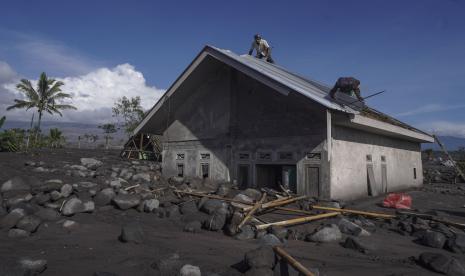 Sejumlah pria menyelamatkan atap rumahnya yang setengah terkubur abu dan material vulkanik letusan Gunung Semeru di Desa Sumberwuluh, Lumajang, Jawa Timur, Selasa, 6 Desember 2022. Gunung Semeru memuntahkan abu tebal lebih dari 1.500 meter (hampir 5.000 kaki) ke langit pada hari Minggu. Desa-desa dan kota-kota terdekat diselimuti abu yang jatuh, menghalangi sinar matahari, tetapi tidak ada korban yang dilaporkan. 